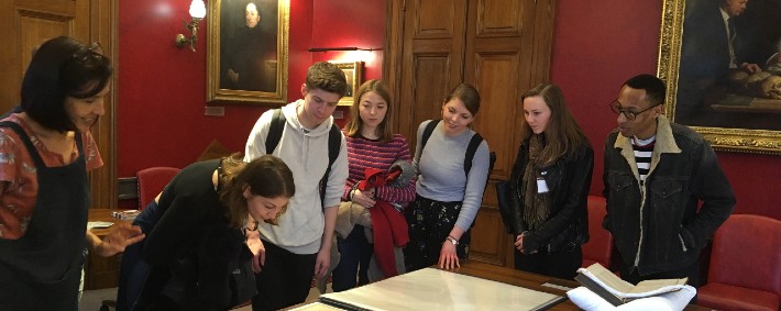 a group of young people looking at maps laid out on a table